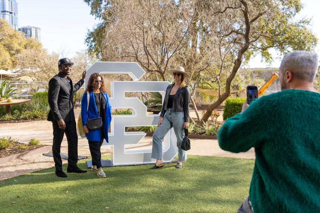 Guests taking an image by the event host's logo at a SXSW private event.
