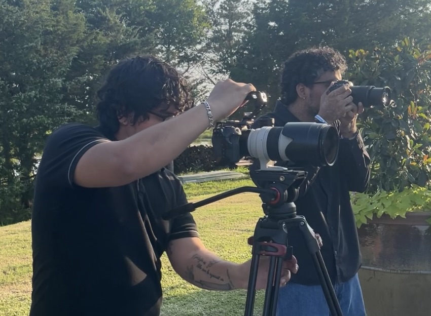 An Austin wedding photo and video team covering a wedding day. The videographer and photographer are both standing next to each other in action!