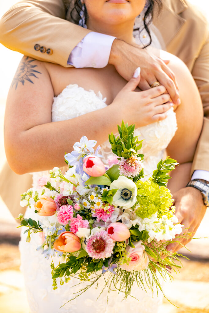 Bride with groom behind, bride's bouquet is in focus. The photo is bright an airy. This photo was taken in by a Texas bilingual wedding photographer.